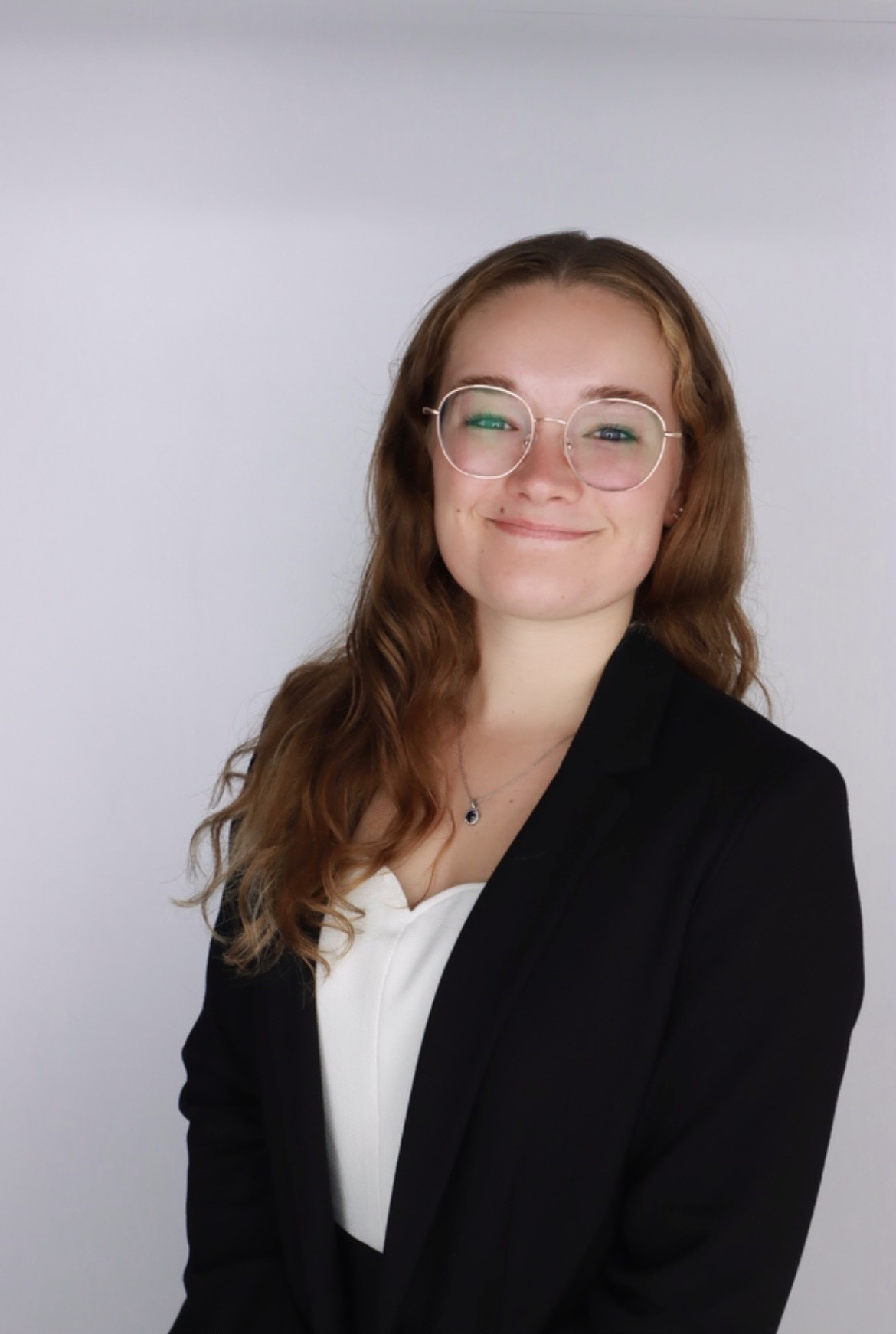 Maggie Sprung, wearing glasses, white shirt, black jacket.