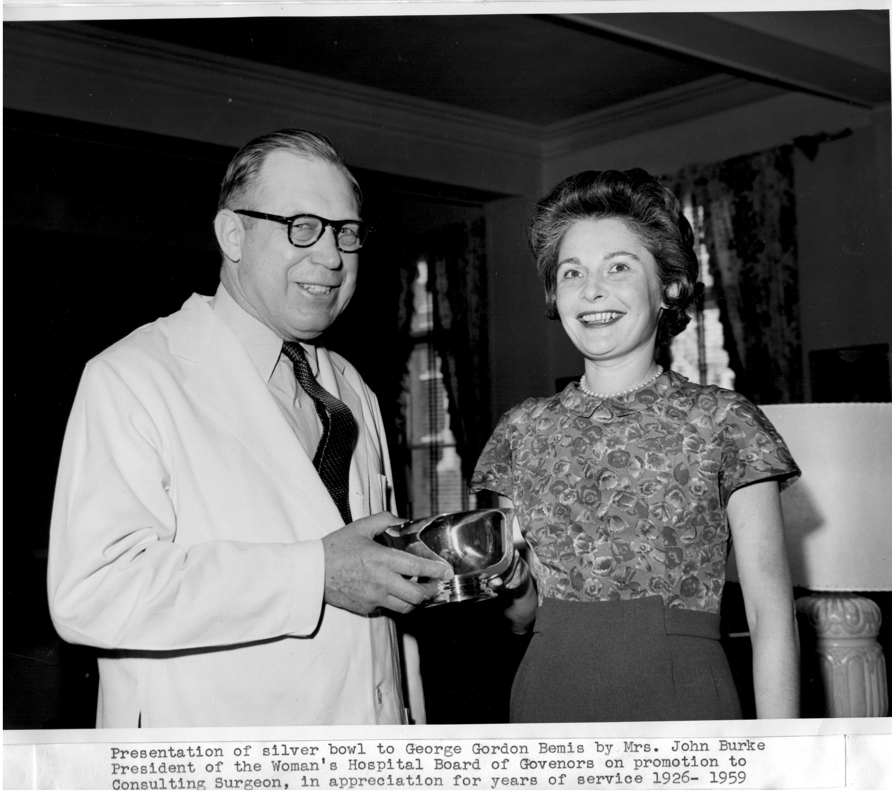 Black and white image of George Bemis, Sr. with a woman. He is holding an award. 