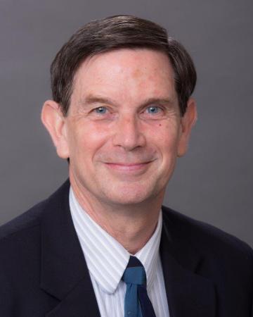 Rogers Smith in a white shirt, black tie and black jacket.