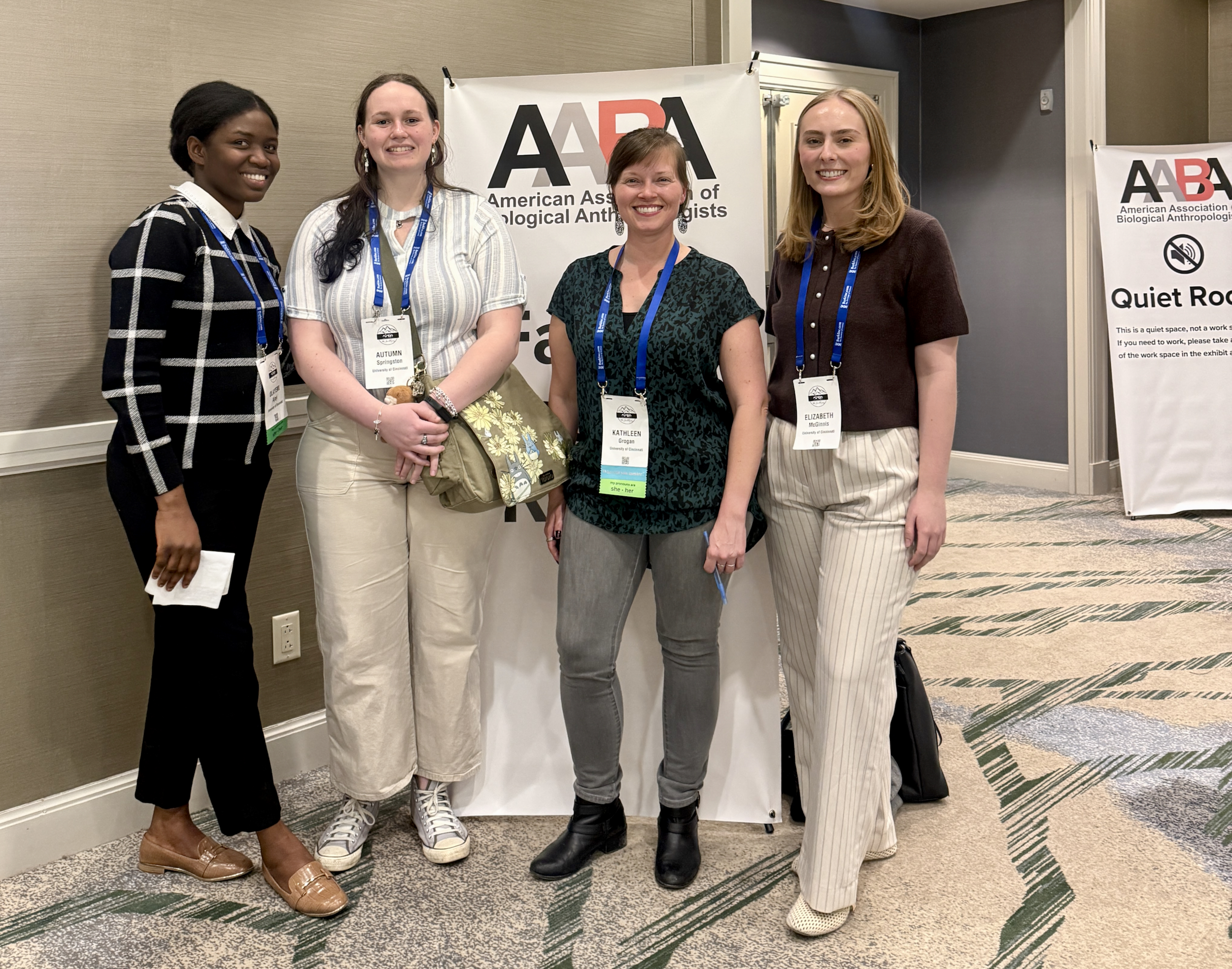Four women stand facing forward wearing name badges at a biological conference in Denver.