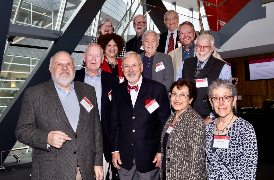 Several board members of the UC Emeriti Association stand together on a stairwell facing forward wearing name badges. 