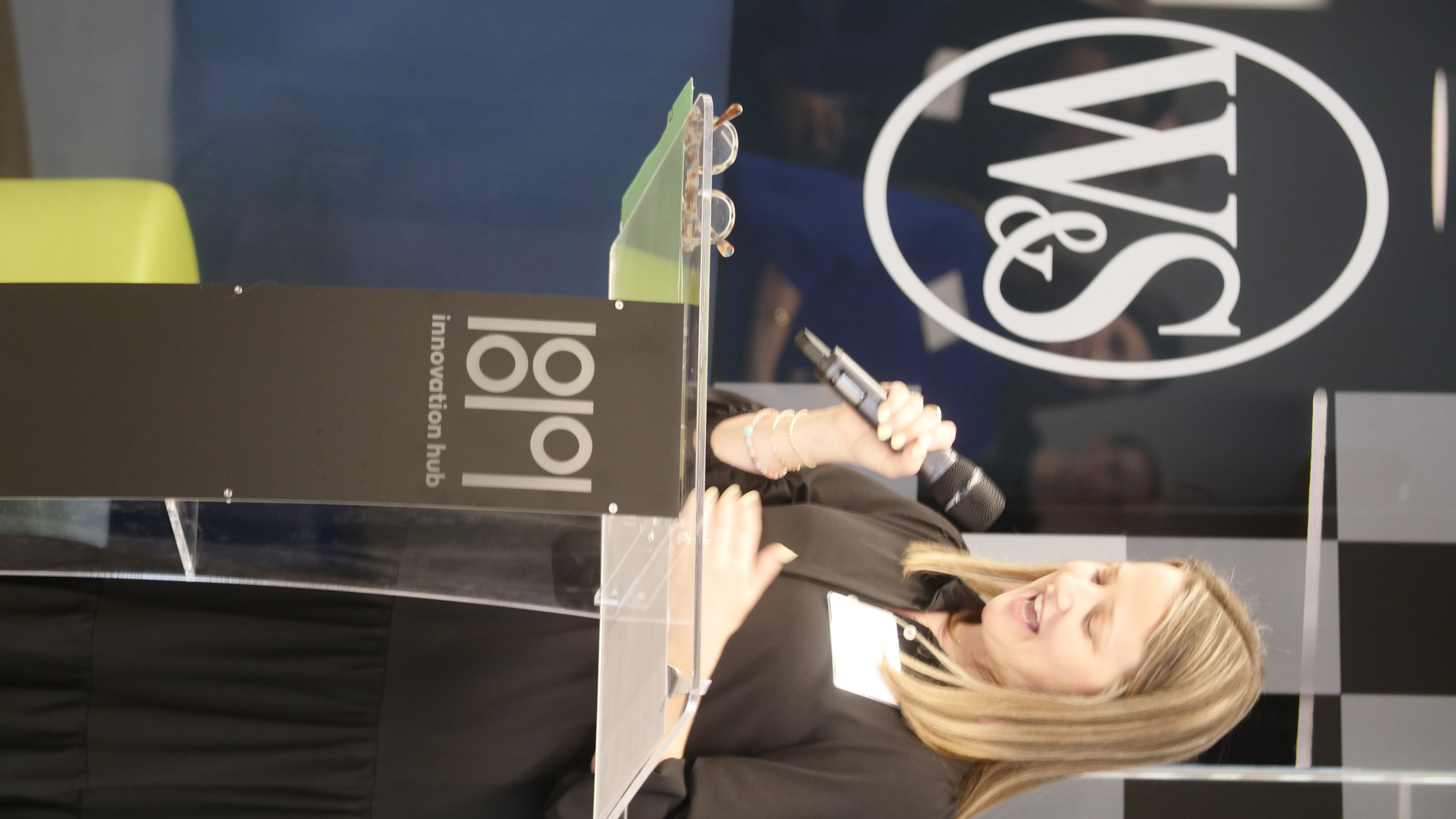 Annie Straka speaking at podium with W&S logo.